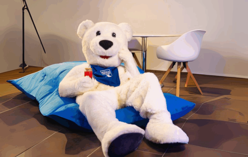 KlimaBär auf Sitzsack und Getränk in der Hand