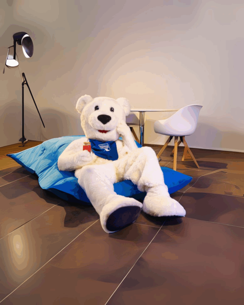 KlimaBär auf Sitzsack und Getränk in der Hand